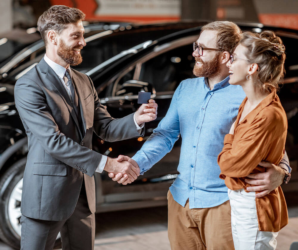 Couple at dealership greeting sales staff