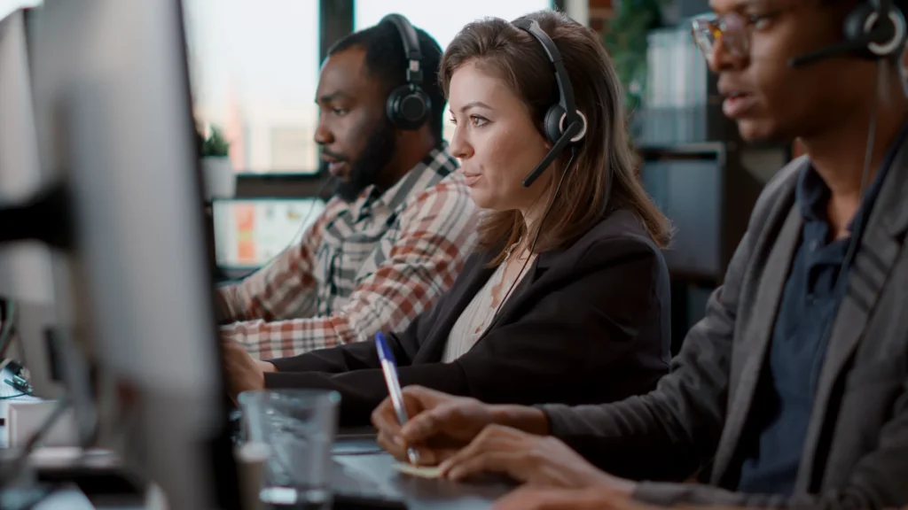 Two male one female BDC call center agents working with headsets and monitors
