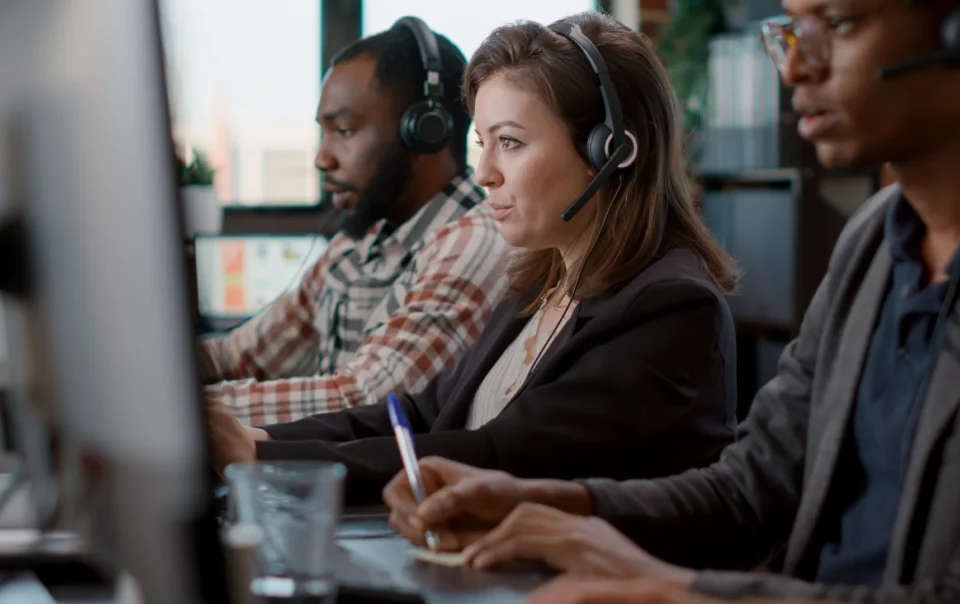 Two male one female BDC call center agents working with headsets and monitors